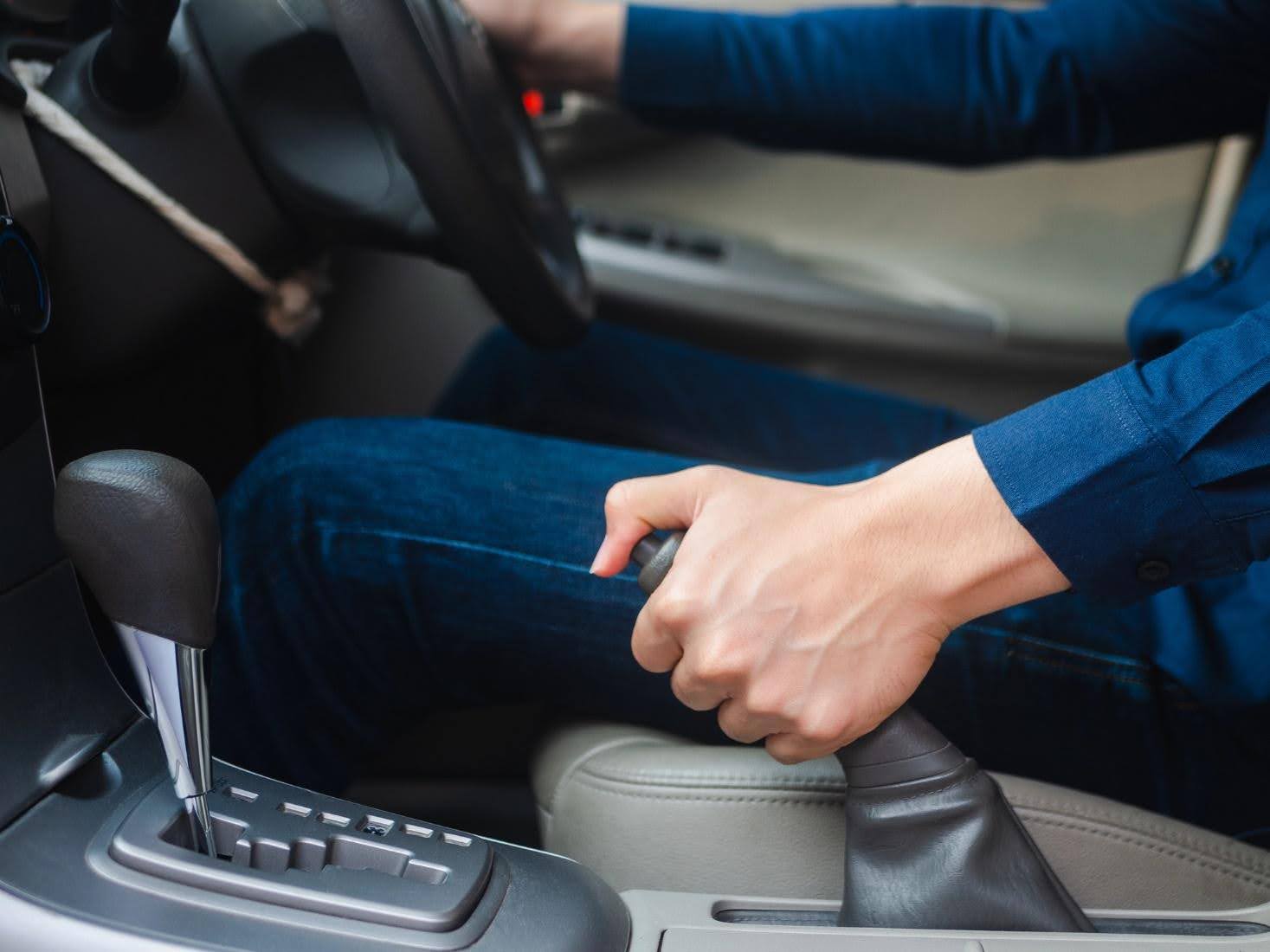 A driver is pulling the emergency brake in a car.